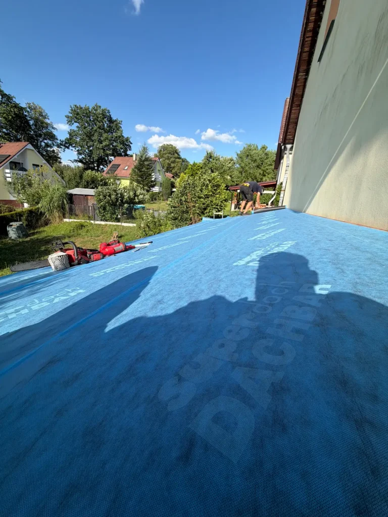 Pokládka podkladní hydroizolace na dřevěný záklop střechy pergoly během montáže
